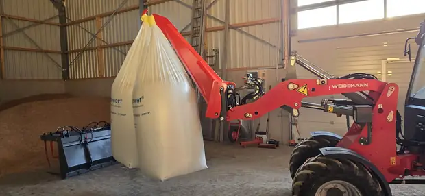 Hoflader hebt einen Big-Bag im Lager, Ausleger über dem Schüttgut