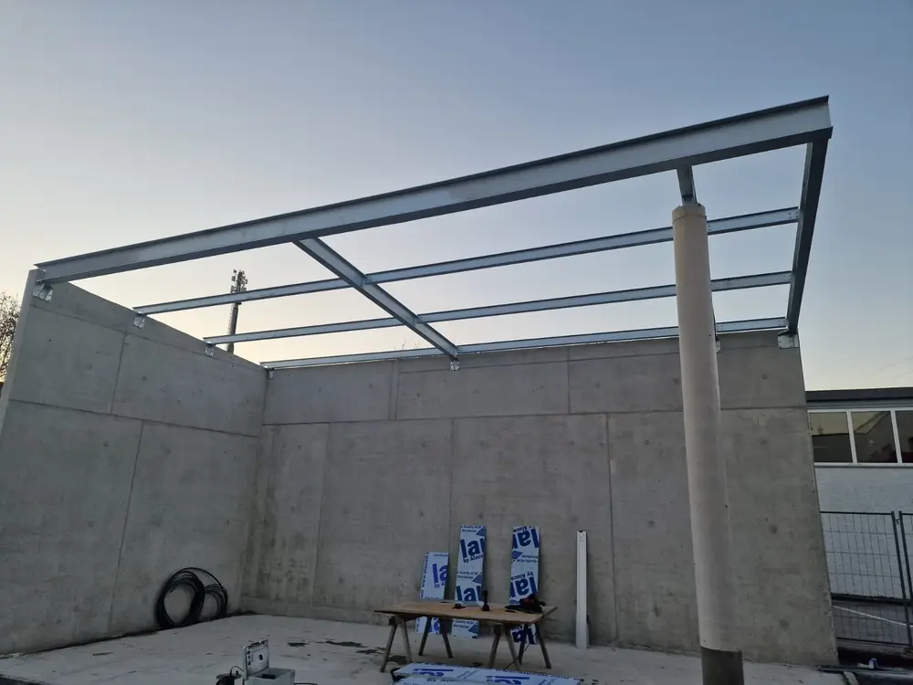 Pultdach aus Stahlprofilen über einem von Betonwänden umfassten Hof, Stütze und Randträger