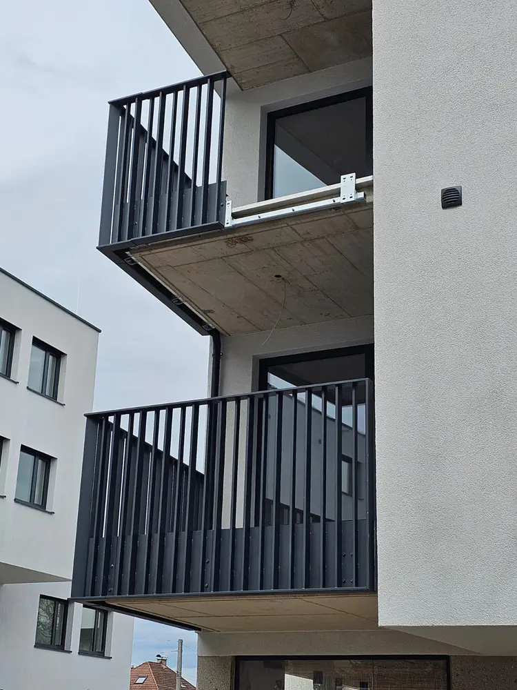 Balkongeländer aus anthrazit beschichtetem Stahl mit senkrechten Füllstäben an einem Wohnhaus, zwei Geschosse übereinander