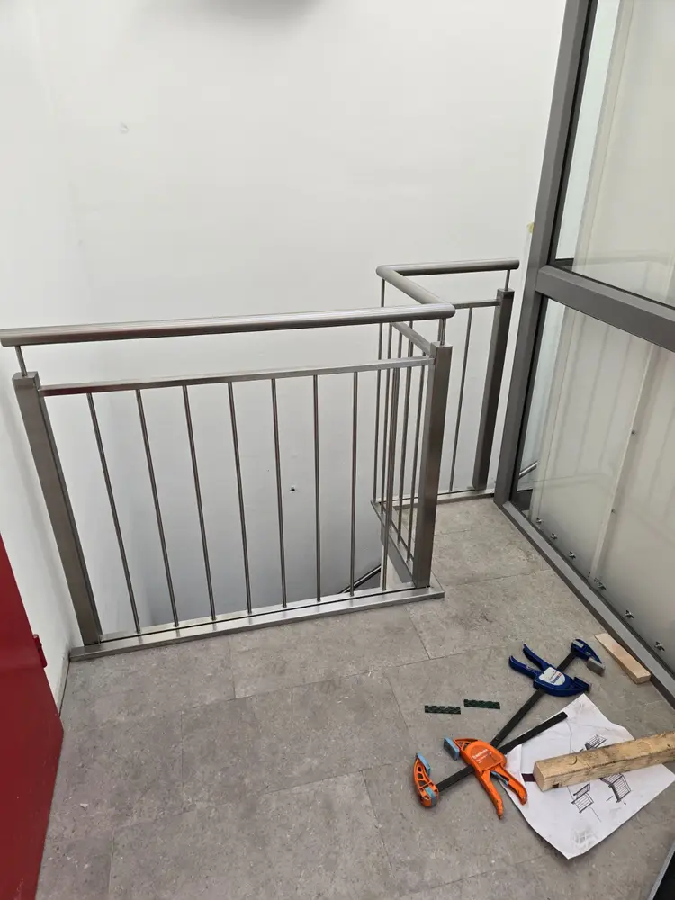 Edelstahlgeländer an einer Balkontür während der Montage, Schraubzwingen und Aufmaßskizze am Boden